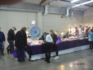 Indoor market with people browsing vendor tables.