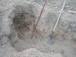 Shovel and tools beside a dug hole.