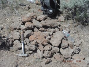 Pile of rocks with hammer and bottle.